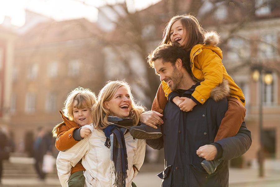 Personal Insurance - Smiling Family Having Fun Taking A Walk Outside In The City