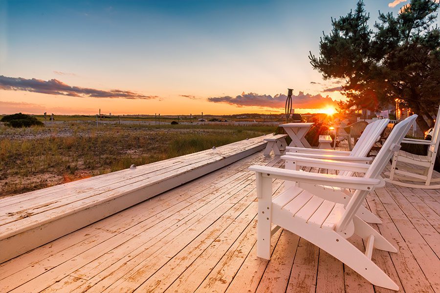 Wrentham MA Insurance - Sunset View of the Water in Massachusetts with Wooden Chairs Sitting on a Porch on a Beautiful Day